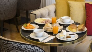 Een ontbijttafel met borden eten, een glas sinaasappelsap en een kop koffie.