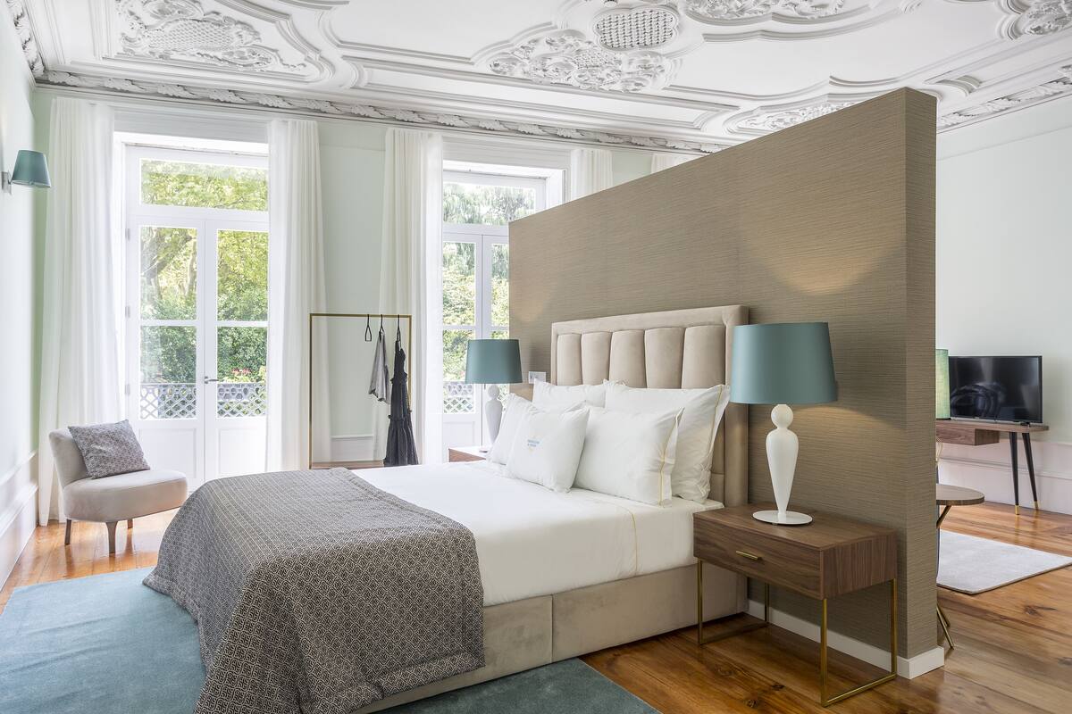 A bedroom with a large bed, two bedside tables, a chair, and a TV.