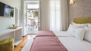 Een hotelkamer met een bed, een televisie, een bureau en een raam met gordijnen.