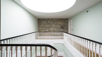 A staircase with white balusters and a black handrail, leading to a room with a stone wall and a door marked with the number 302.