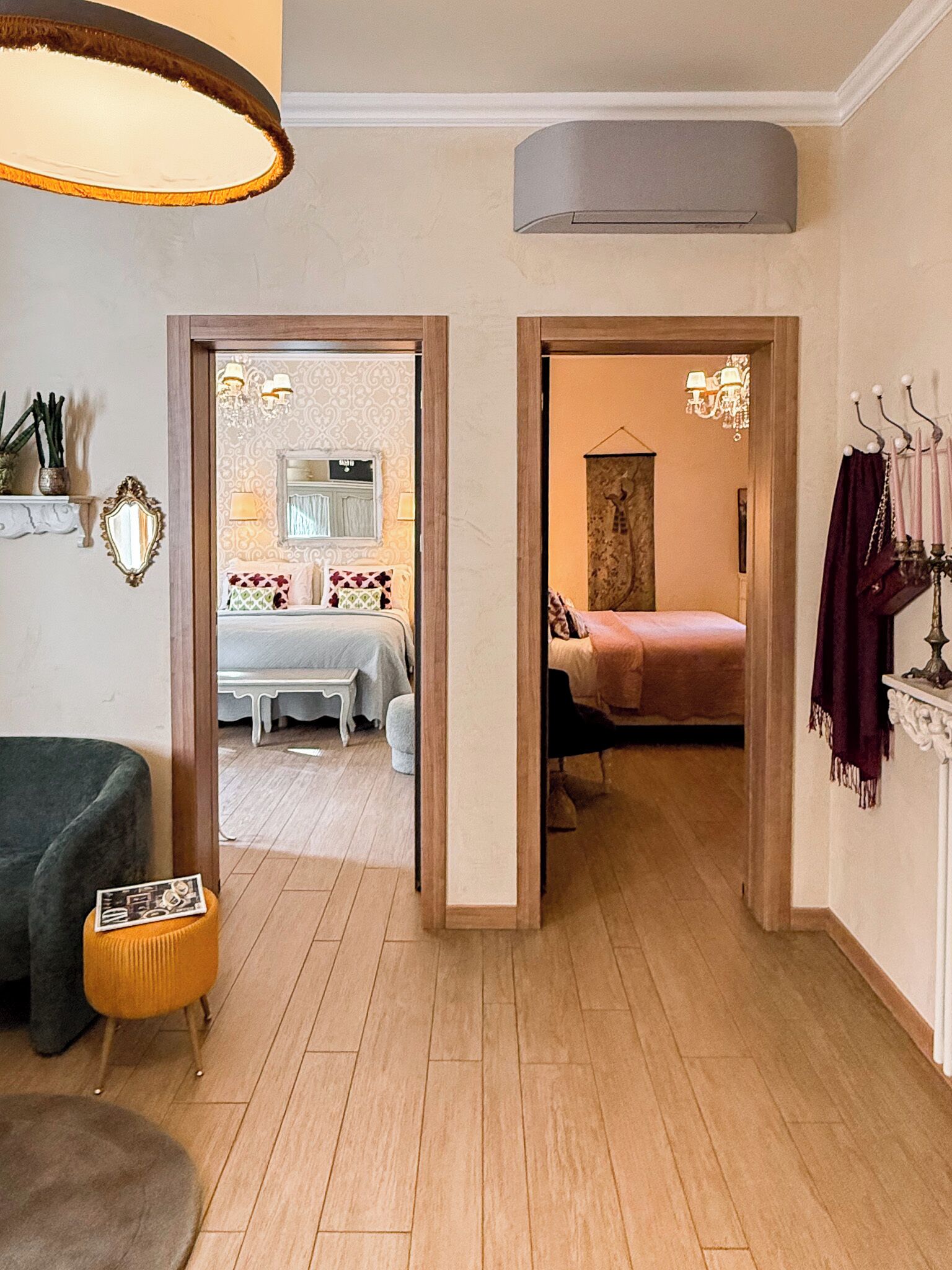 Una habitación con cama, una silla, una mesa y una lámpara. Hay una puerta que da a otra habitación.