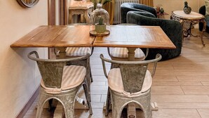 Zona pranzo con tavolo in legno e sedie d'epoca, un lampadario e un grande specchio.