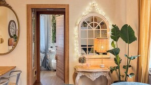 Una camera accogliente con una porta in legno che dà su un bagno, un comò con uno specchio e un tavolo con una lampada.