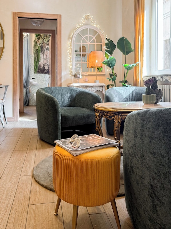 A cozy living room with a sofa, ottoman, and a table with a magazine.