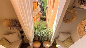 Una stanza piccola con vista su un cortile interno, un tavolino e due sedie in vimini.