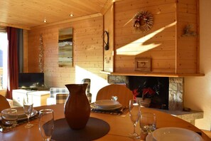 A wooden interior with a fireplace, dining table set with plates, glasses, and a vase. - 2nd floor, view mountain, balcony, tv, ski locker, 51m², Méribel (Méribel - Les Allues)