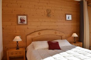 A wooden-paneled room with a bed, two bedside tables, and wall-mounted lamps. - 2nd floor, view mountain, balcony, tv, ski locker, 51m², Méribel (Méribel - Les Allues)