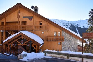 A wooden lodge with a stone extension, a covered entrance, and a sign indicating private parking. - 2nd floor, view mountain, balcony, tv, ski locker, 51m², Méribel (Méribel - Les Allues)