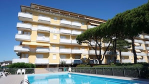 Un immeuble à plusieurs étages, doté de balcons et d’une piscine à l’avant.