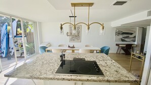 A modern kitchen with a granite countertop, white cabinetry, and a built-in induction cooktop. - Lovely two story home on the water (Hallandale Beach)