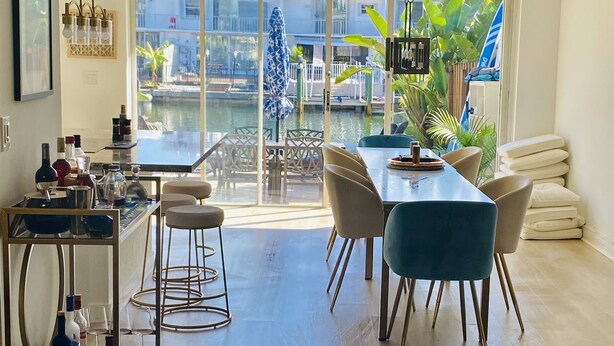 A modern dining area with a view of a water body, a bar with bottles, and a seating arrangement. - Lovely two story home on the water (Hallandale Beach)