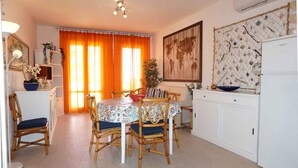 A dining area with a round table, four chairs, and a kitchen counter with a refrigerator.