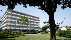 A multi-story building with balconies, surrounded by a well-maintained lawn and trees.