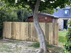 Una valla de madera en un patio con una casa al fondo.