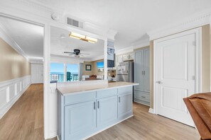 A kitchen with a large island, white cabinetry, and a view to the outside.