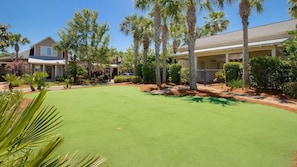 Zona residencial con césped cuidado, palmeras y casas con porches.