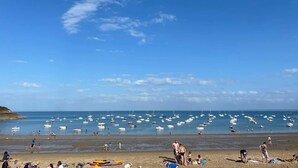 Ein Strand mit Menschen, Booten und blauem Himmel.