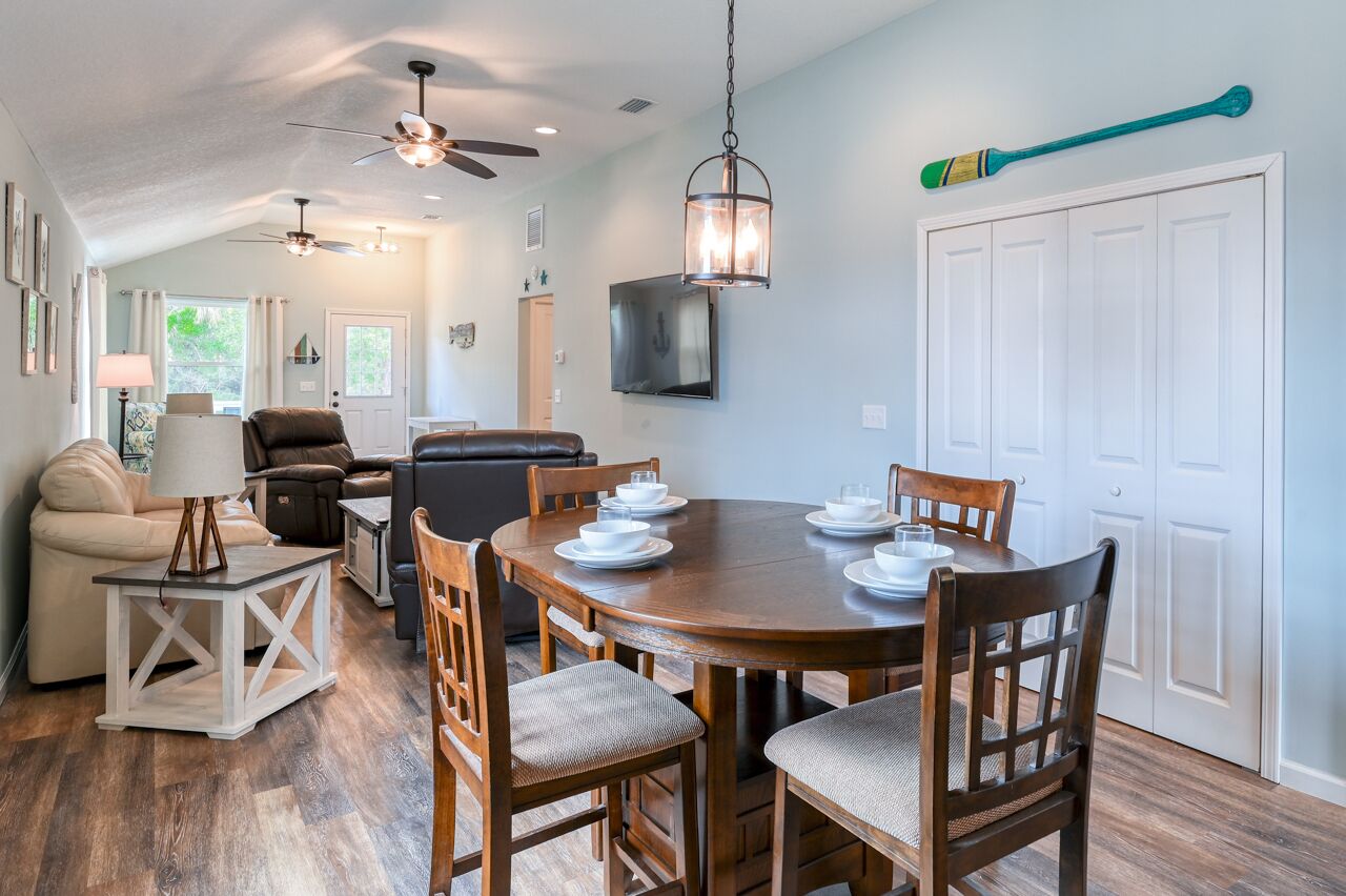 A dining area with a round wooden table set for four, surrounded by wooden chairs.
