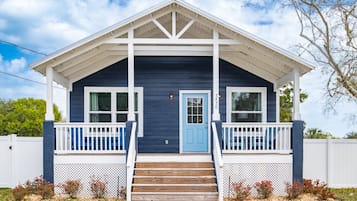 A two-story house with a blue door and white railings on the porch.