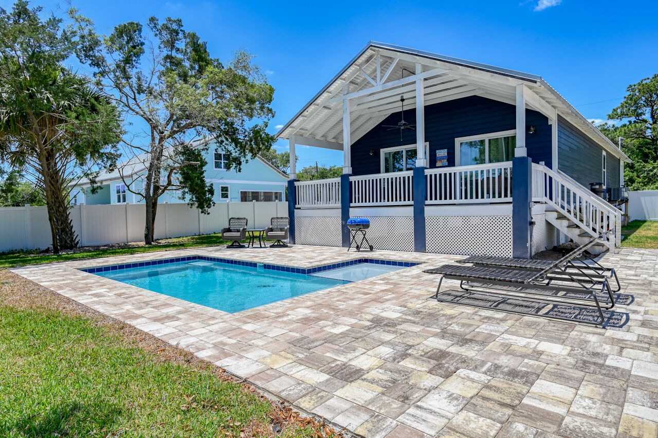 Ein Haus mit überdachter Terrasse, Swimmingpool und Grill.