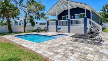 Ein Haus mit überdachter Terrasse, Swimmingpool und Grill.