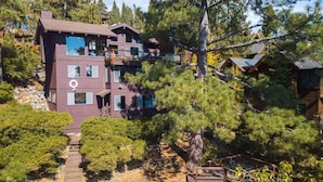 A multi-story building with a wooden exterior, surrounded by dense trees and a wooden deck. - Lakefront Retreat in Tahoe City- large home in Dollar Point (Tahoe City)