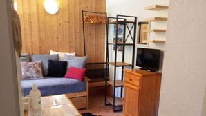 Une pièce confortable avec un lit, une armoire en bois, une télévision et une étagère remplie de livres.