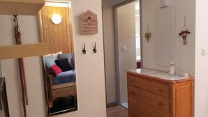 Une chambre à coucher comprenant un lit, une commode en bois, un miroir et un luminaire fixé au mur.