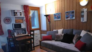 Un salon confortable avec un canapé, une table à manger, un four à micro-ondes et un petit coin cuisine.