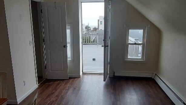 Una habitación vacía con techo inclinado, ventilador de techo, puerta que da al exterior y ventana.