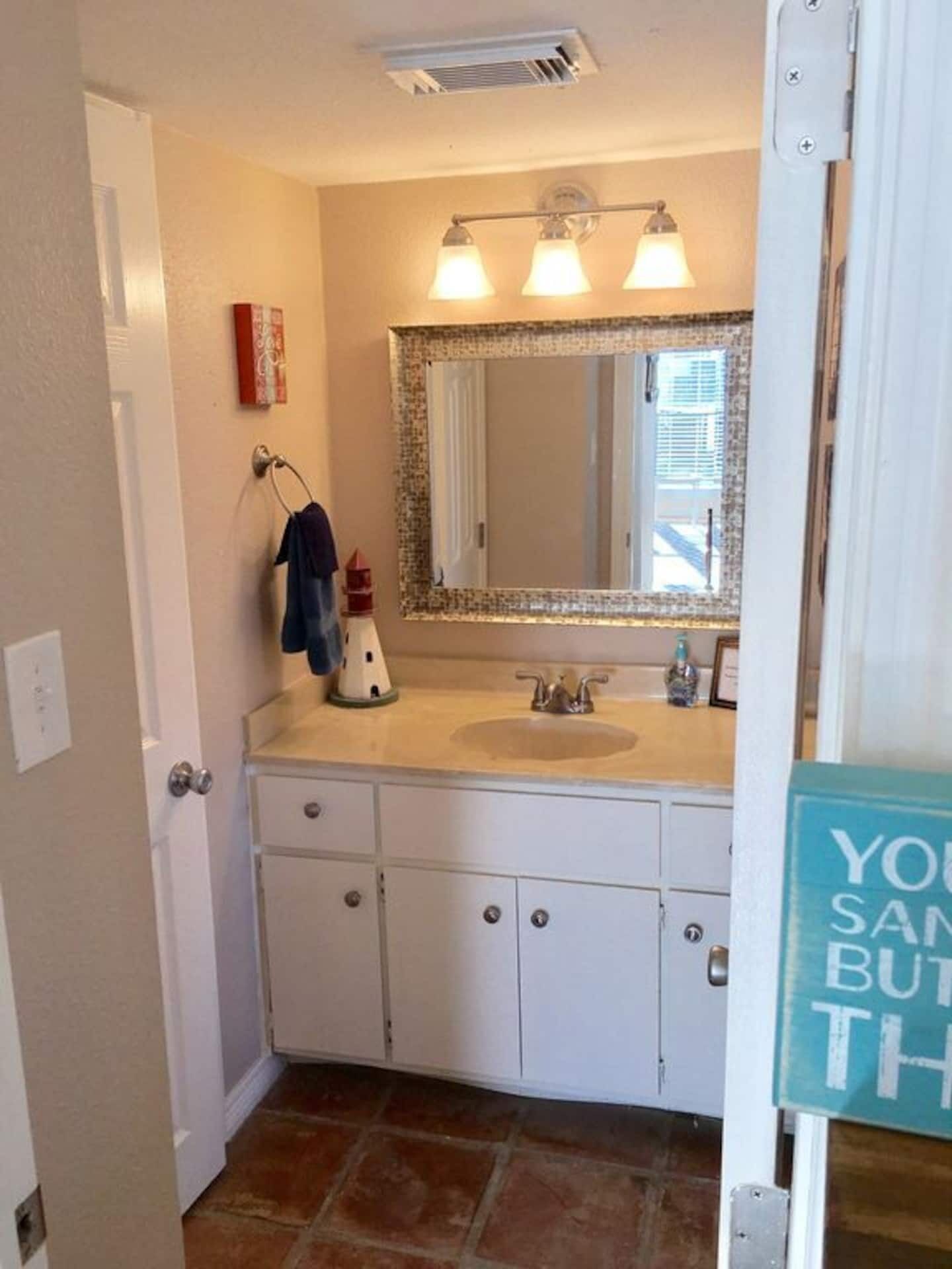 A bathroom with a white vanity, a mirror with a decorative frame, and a towel rack with a towel hanging on it.