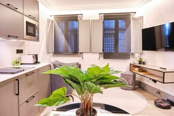 A modern kitchen with a central island, a microwave, a toaster, and a potted plant.