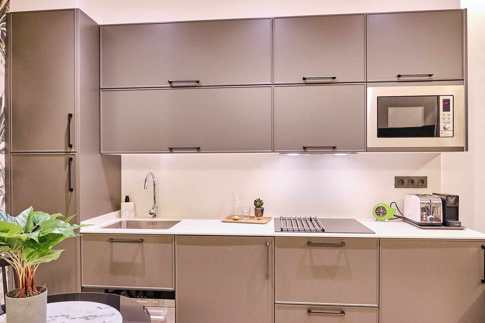 A modern kitchen with grey cabinets, a microwave, a toaster, and a sink.