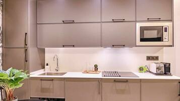 A modern kitchen with grey cabinets, a microwave, a toaster, and a sink.