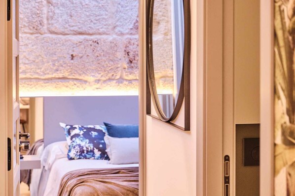 A hotel room with a bed, a nightstand, a lamp, and a mirror.