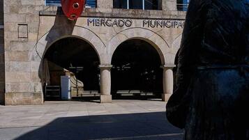 Um edifício com a inscrição 'MERCADO MUNICIPAL' e uma estátua de uma pessoa em frente.