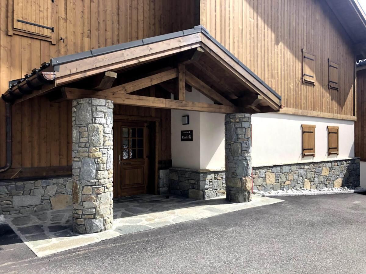 Un bâtiment à la façade en pierre et en bois, doté d’une entrée couverte et d’une enseigne indiquant « Chalet G ».