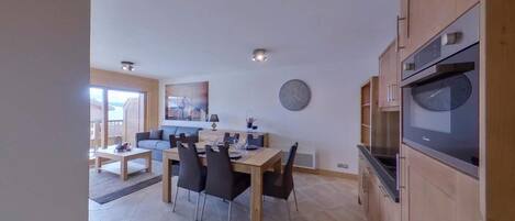 Une cuisine moderne avec un coin repas, des meubles en bois et un grand four.