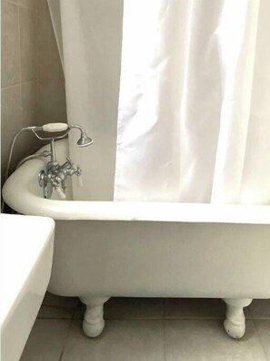 Tina con regadera, secadora de cabello, toallas, papel de baño 