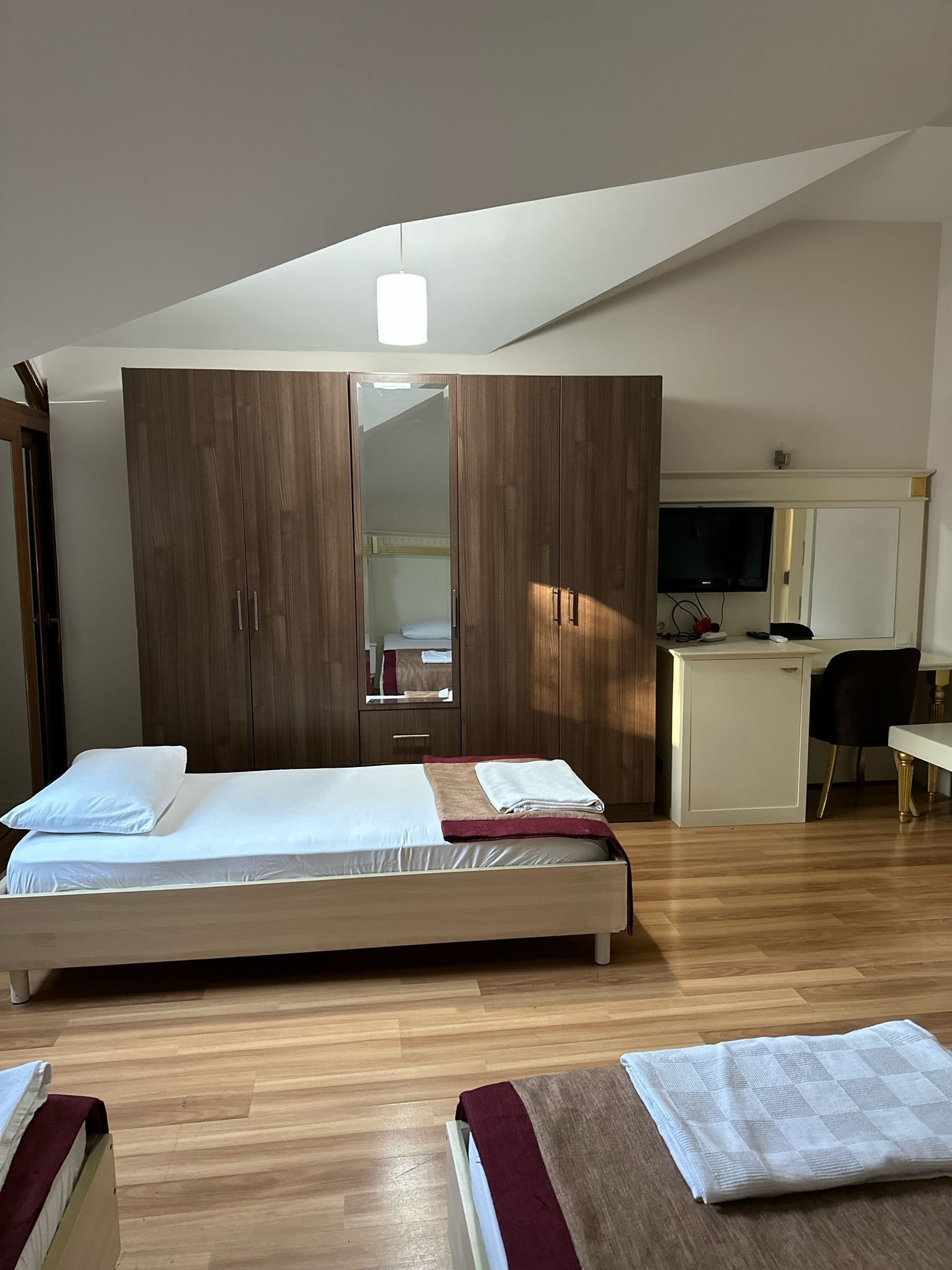 Un dormitorio con cama, armario, escritorio y televisor.