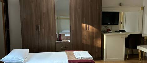 Un dormitorio con cama, armario, escritorio y televisor.