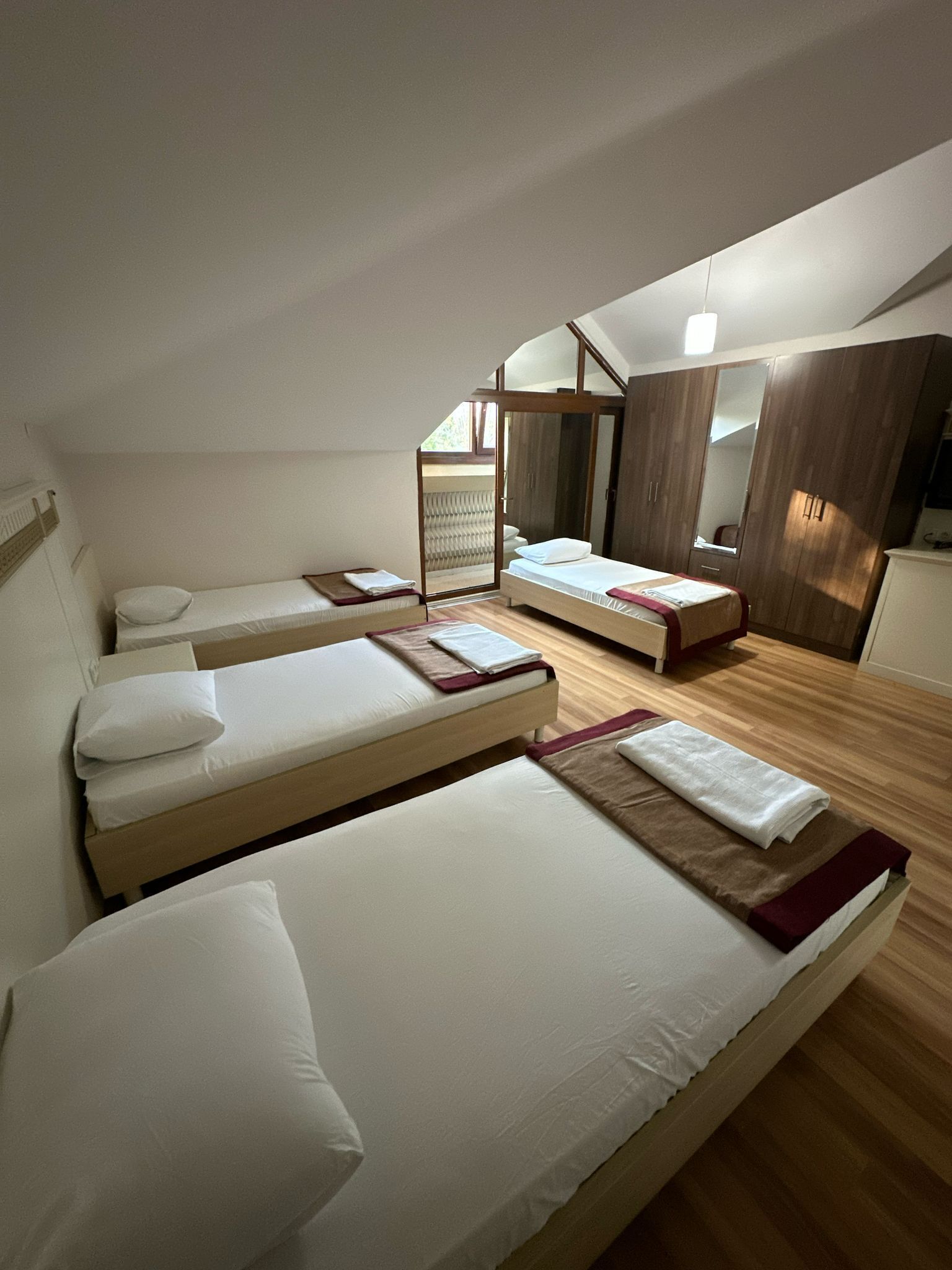 A bedroom with two single beds, a wooden wardrobe, and a large mirror.