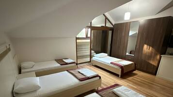 Un dormitorio con dos camas individuales, un armario de madera y un espejo grande.