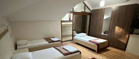 A bedroom with two single beds, a wooden wardrobe, and a large mirror.