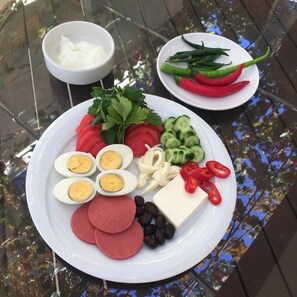 Une assiette garnie de tranches de concombre, de tomates, de persil, d’olives, de poivrons rouges, de fromage et de salami en tranches.