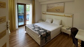 A hotel room with a large bed, bedside tables, a desk, and a view through a sliding glass door. - Barby Butik Otel (Kemer)