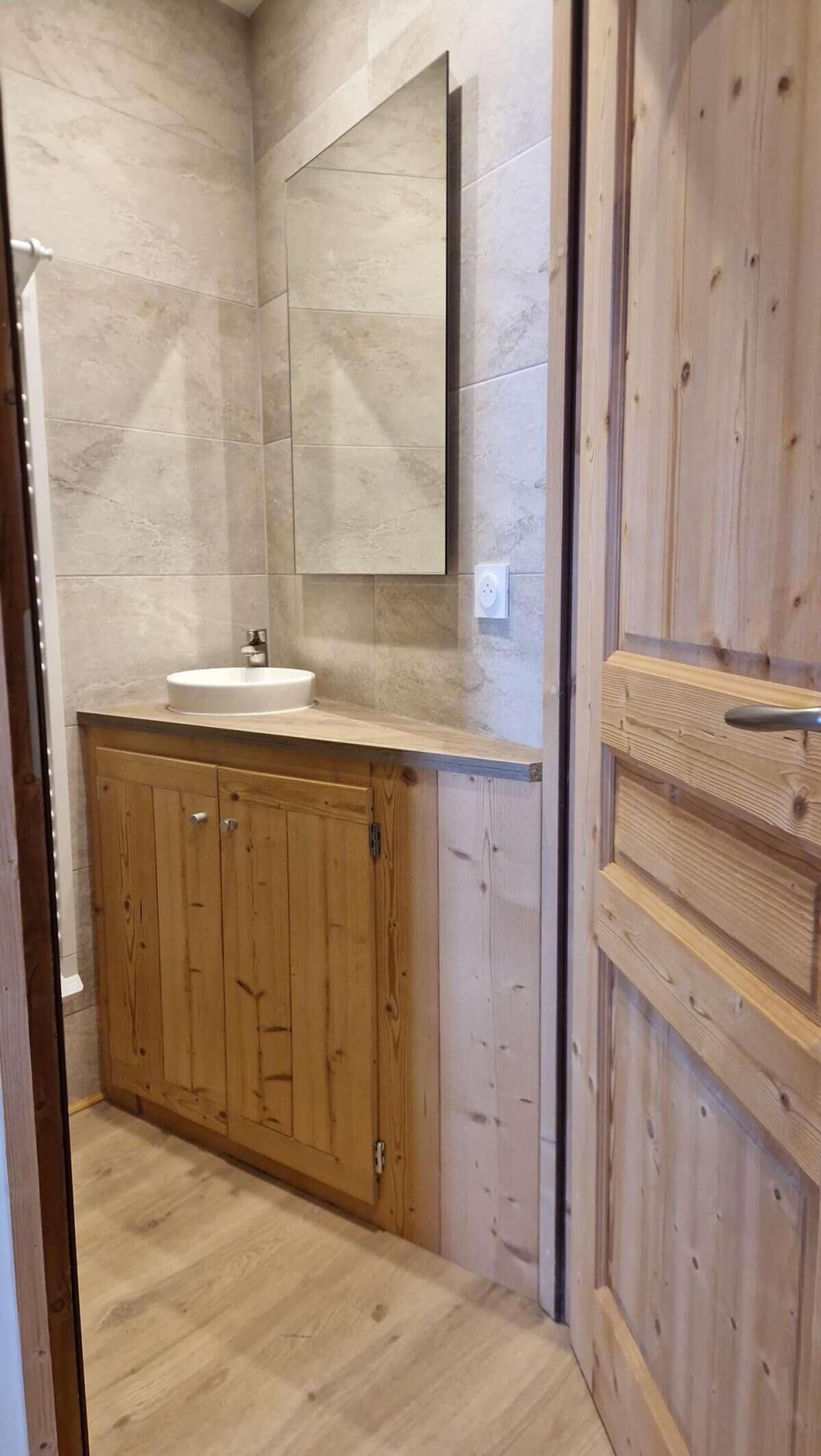 A bathroom with a wooden vanity, a sink, and a mirror.