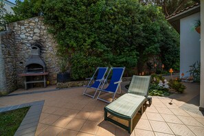 A patio with a stone wall, a pizza oven, and two lounge chairs. - Appartamento Villa da 6 a 8 Persone Capoliveri (Capoliveri)