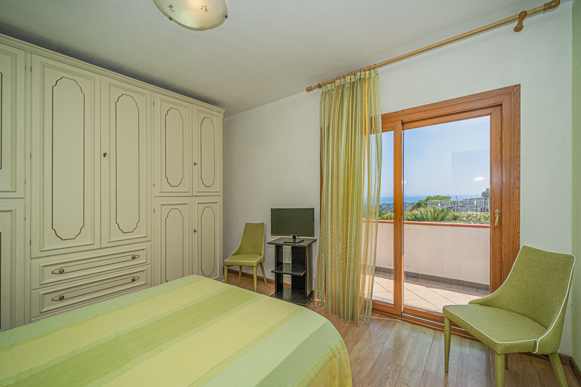A bedroom with a bed, a desk, a chair, and a wardrobe.