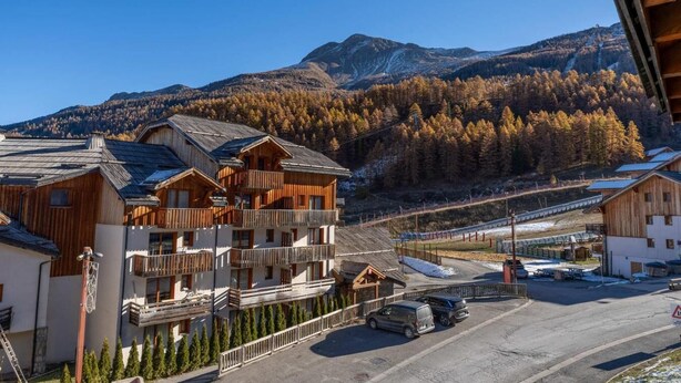 Et bjergresort med træhuse, stolelift og udsigt til de omkringliggende bjerge.